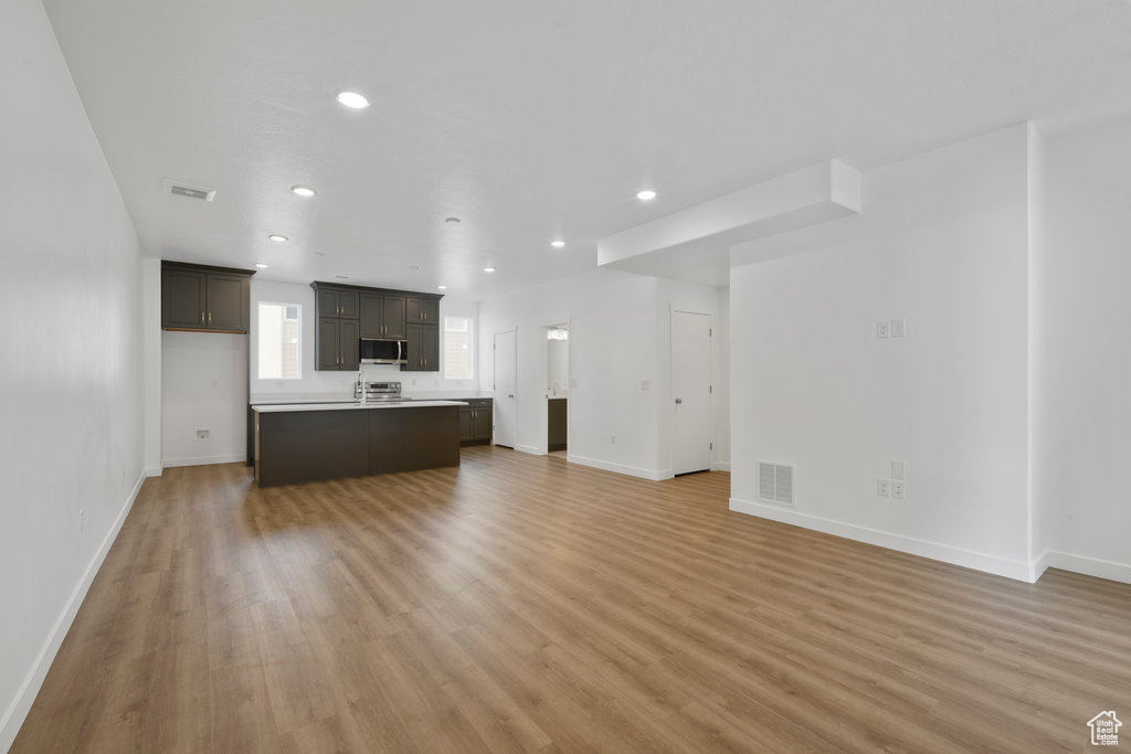 Unfurnished living room with light wood finished floors, recessed lighting, and baseboards