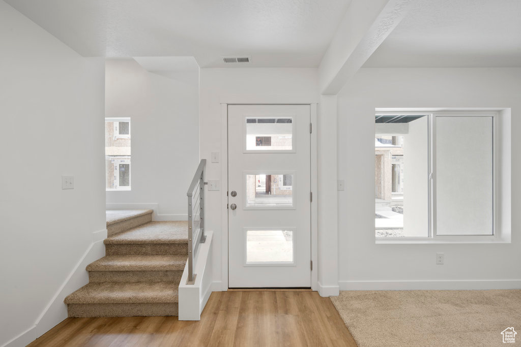 Foyer with stairs, light wood-style flooring, and baseboards