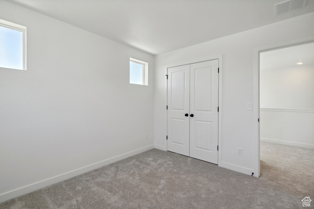 Unfurnished bedroom featuring carpet flooring, baseboards, and a closet