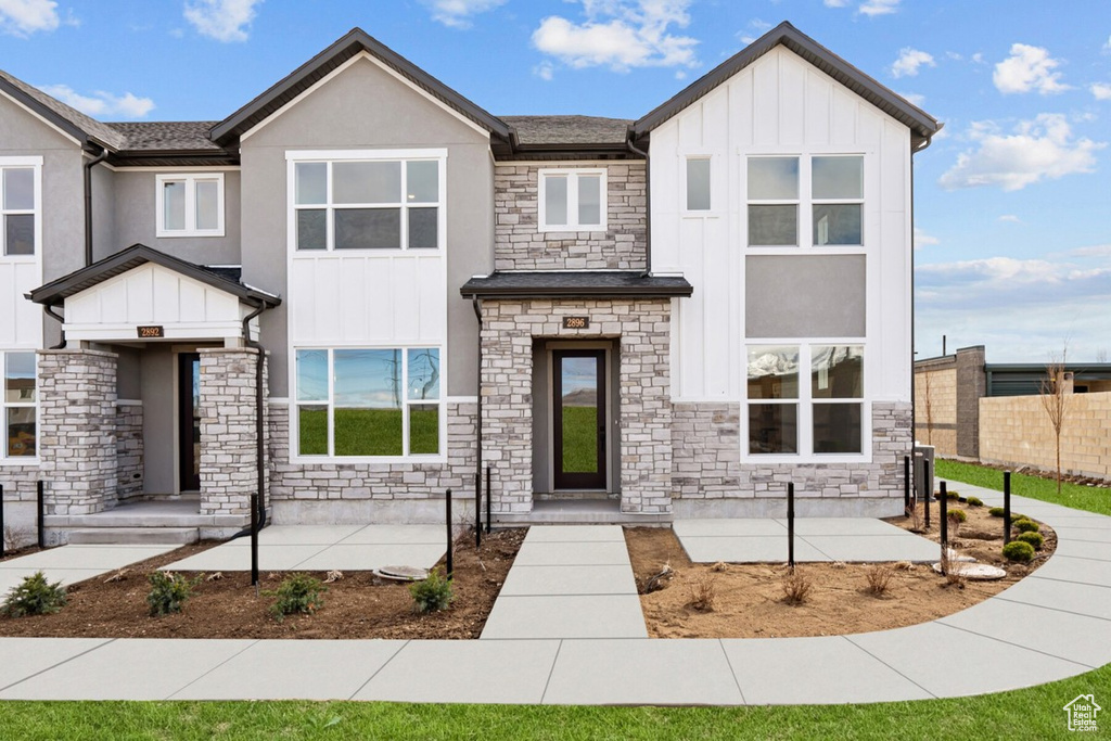 View of front of house featuring stone siding, board and batten siding, and stucco siding