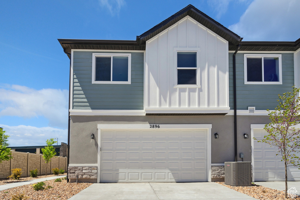 View of front of property featuring central AC unit, board and batten siding, concrete driveway, and an attached garage