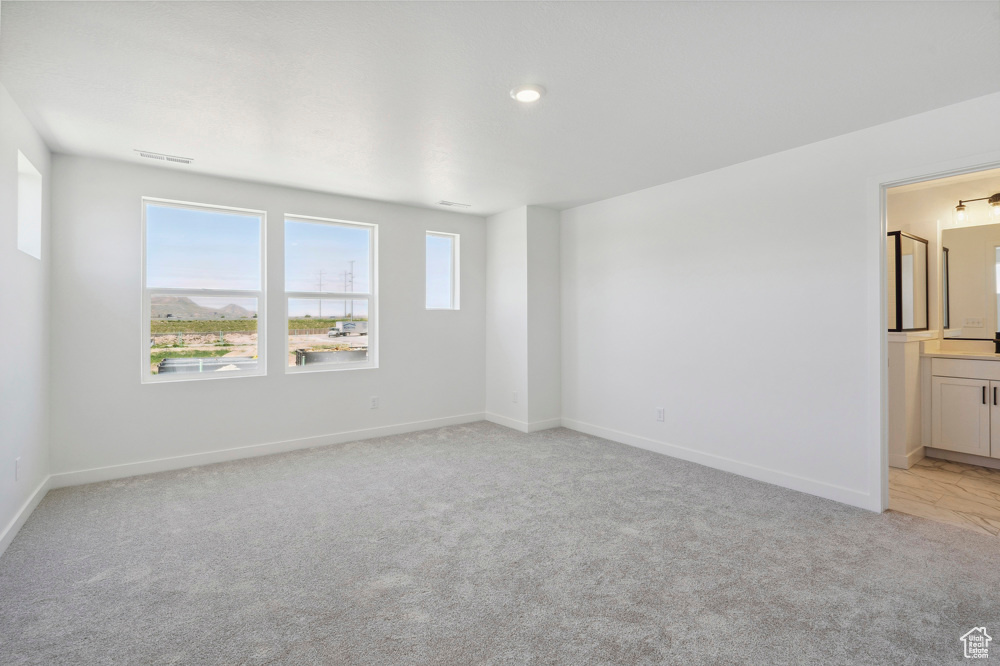 Spare room featuring light colored carpet, baseboards, and recessed lighting