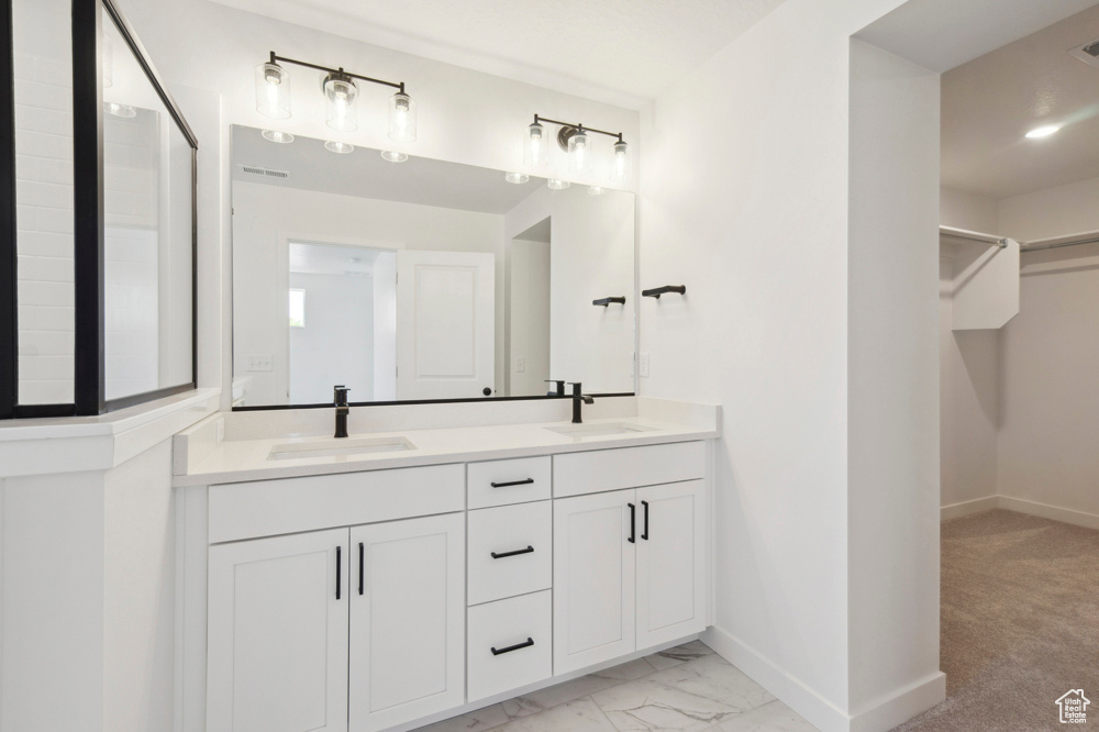 Bathroom with double vanity, baseboards, a spacious closet, and marble finish flooring