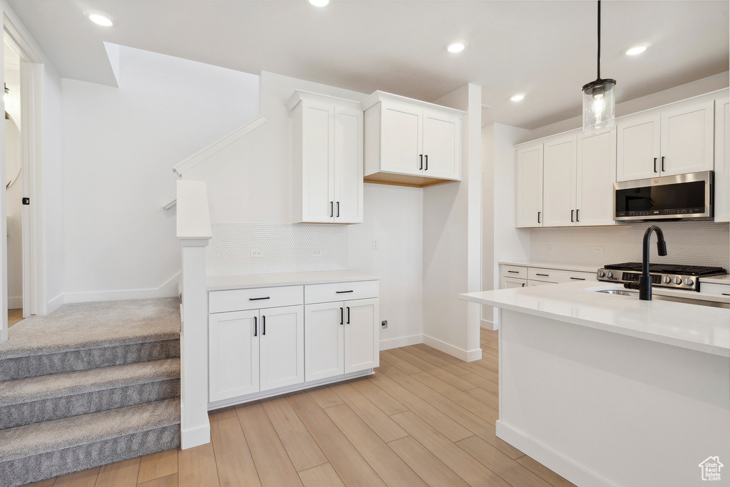 Kitchen with stainless steel microwave, baseboards, backsplash, light countertops, and recessed lighting