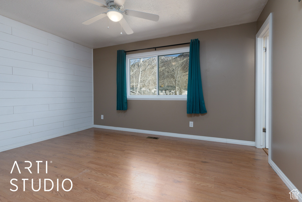 Unfurnished room with light wood-style floors, a ceiling fan, and baseboards