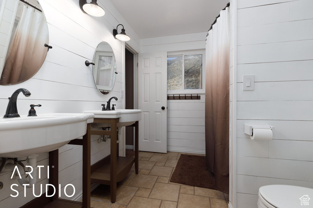 Full bathroom with stone finish floors, toilet, and wood walls