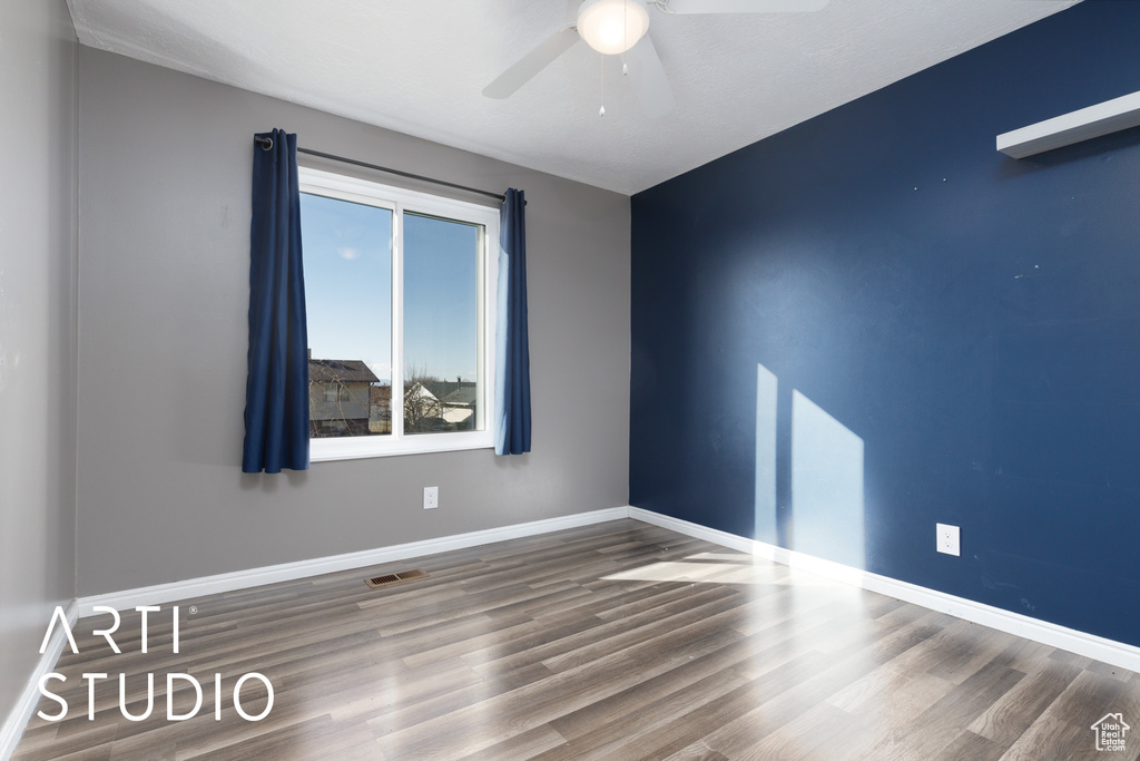Unfurnished room with a ceiling fan, wood finished floors, and baseboards