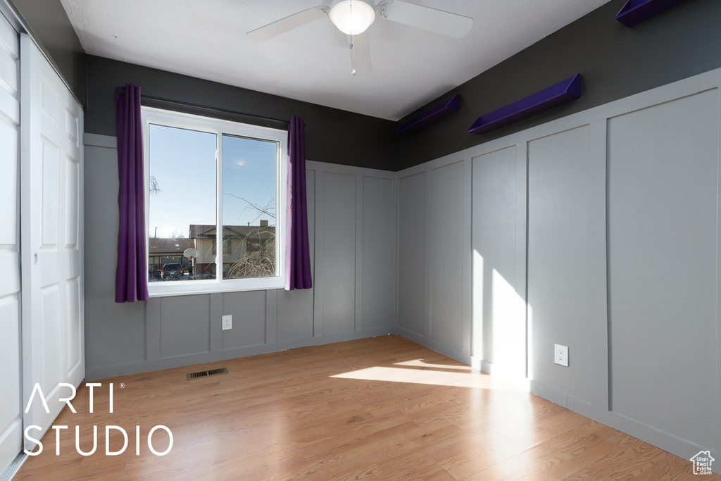 Empty room featuring a decorative wall, ceiling fan, and wood finished floors