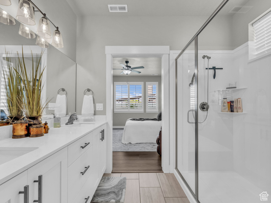 Ensuite bathroom with a ceiling fan, double vanity, and a stall shower