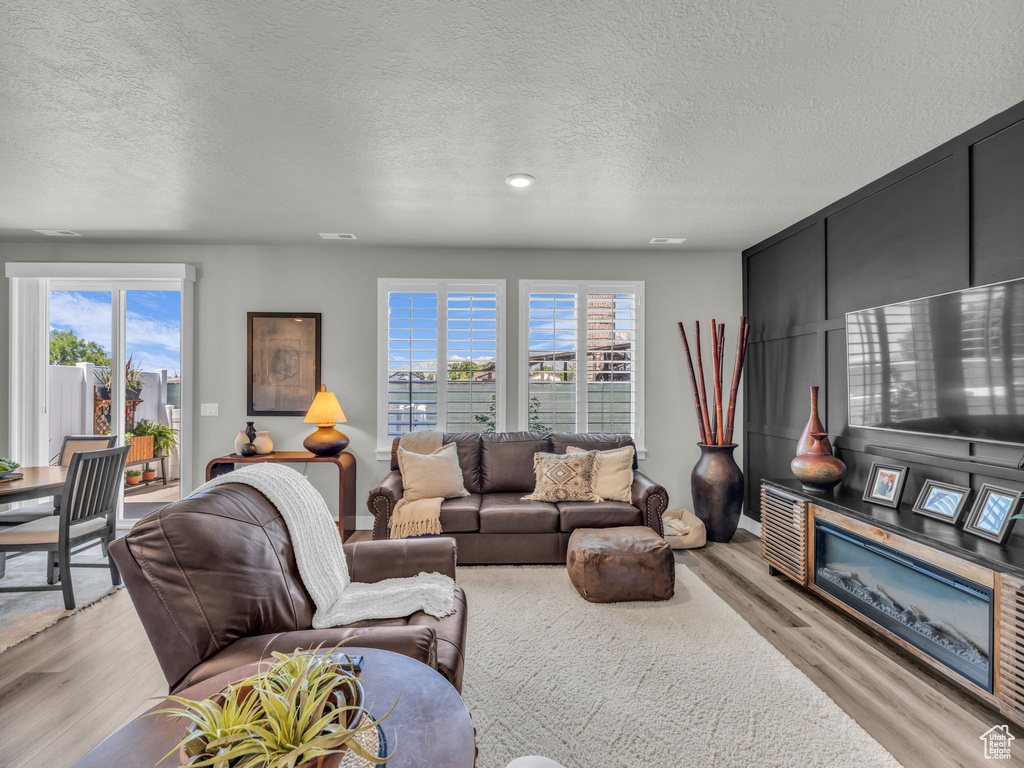 Living room with light wood-type flooring, a textured ceiling, and recessed lighting