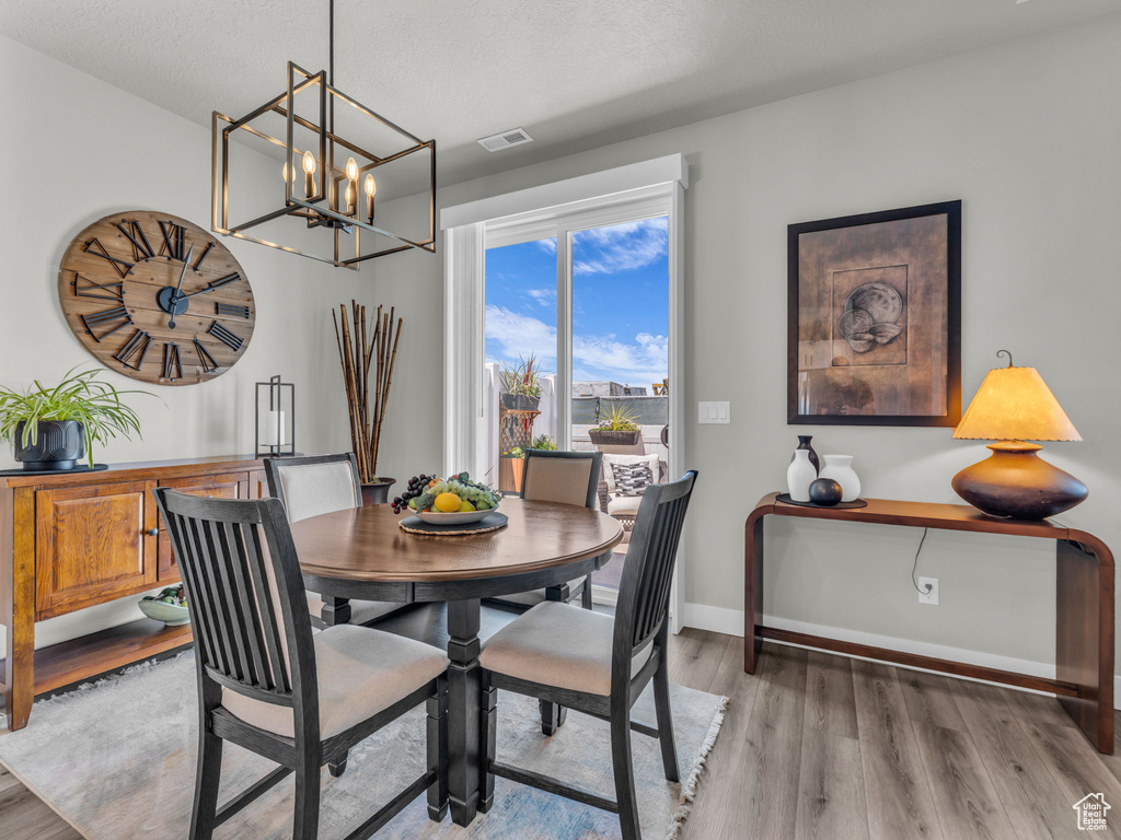 Dining area featuring light wood-style flooring, a chandelier, and baseboards