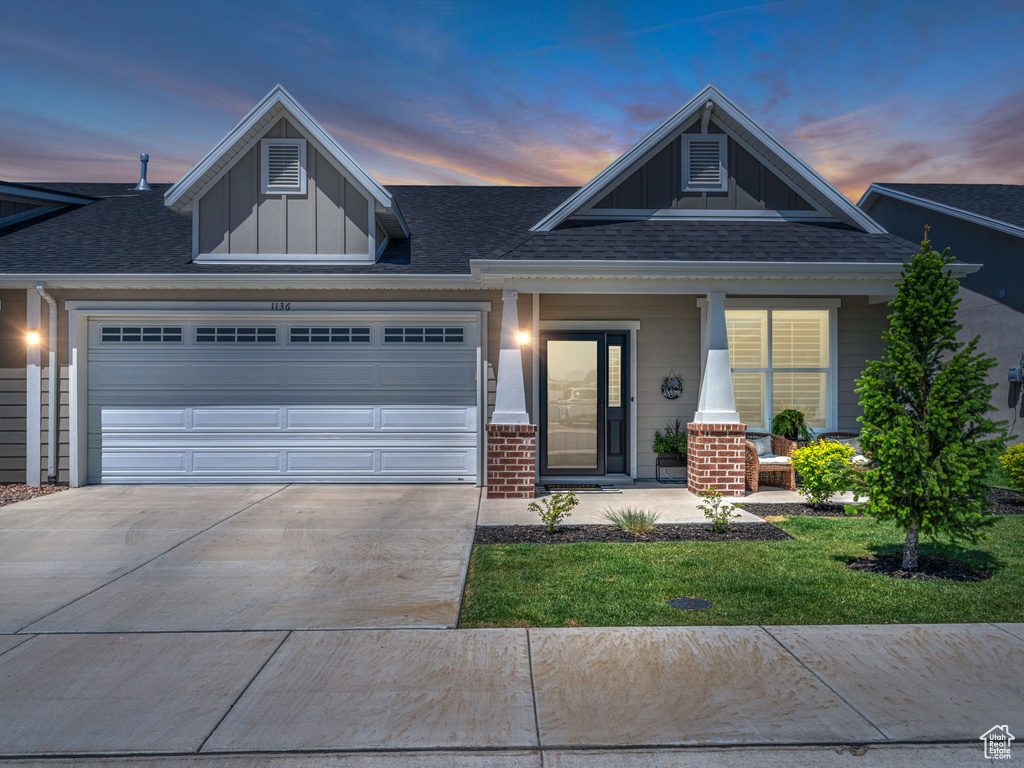 View of front of home featuring board and batten siding, a garage, concrete driveway, and roof with shingles