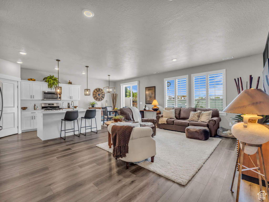Living area with wood finished floors, a textured ceiling, recessed lighting, and a chandelier