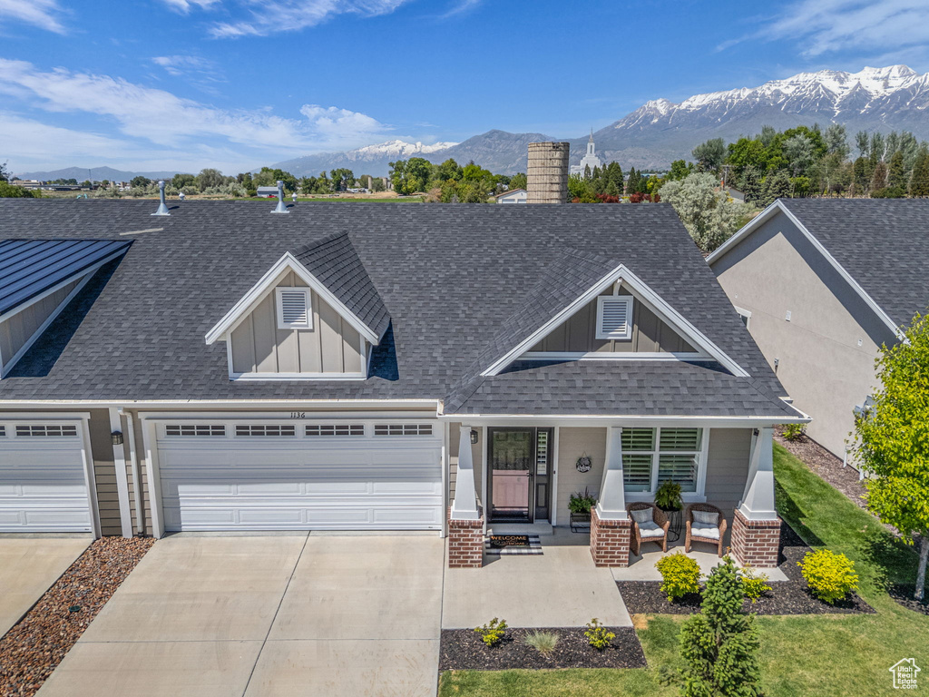 Craftsman inspired home with roof with shingles, concrete driveway, covered porch, a mountain view, and board and batten siding
