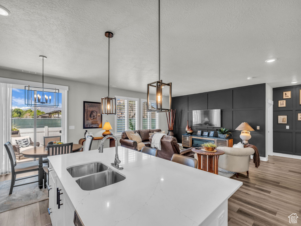 Kitchen with a sink, a chandelier, healthy amount of natural light, a textured ceiling, and light wood-type flooring
