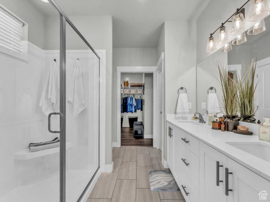 Bathroom with a stall shower, double vanity, a spacious closet, and baseboards