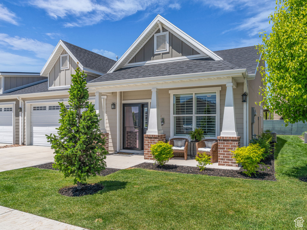 Craftsman inspired home with board and batten siding, a porch, concrete driveway, an attached garage, and a front lawn
