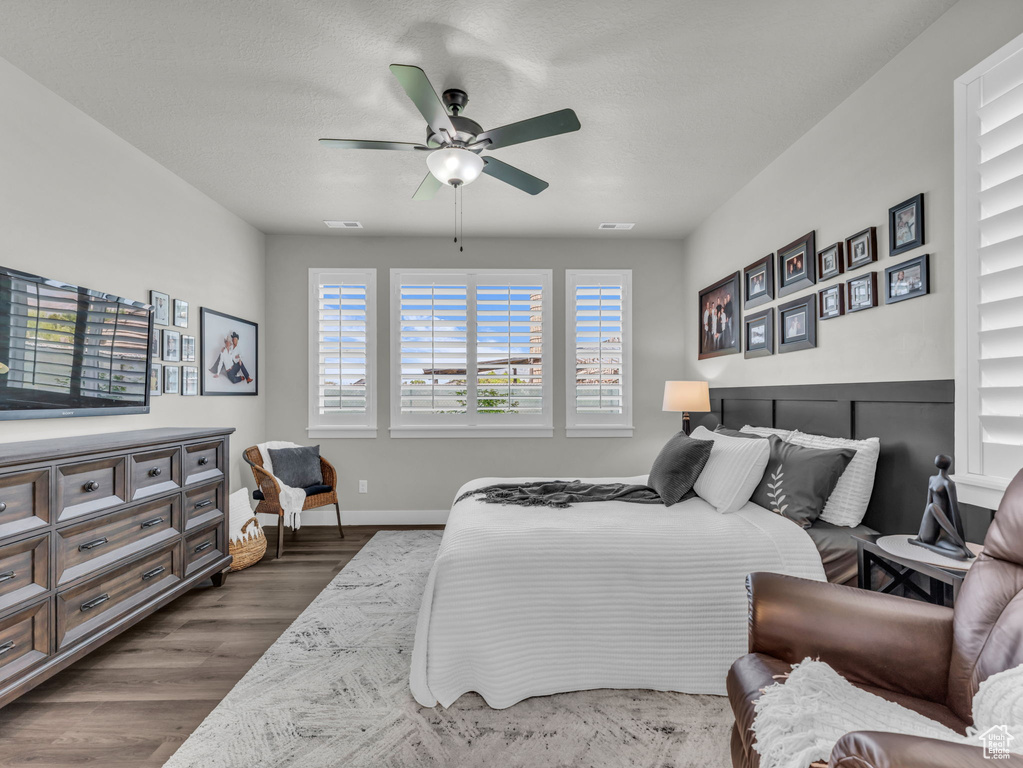 Bedroom with dark wood finished floors, baseboards, and a ceiling fan