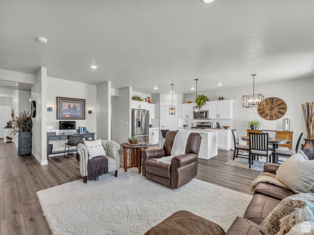 Living room with dark wood-style floors, a chandelier, recessed lighting, a textured ceiling, and baseboards