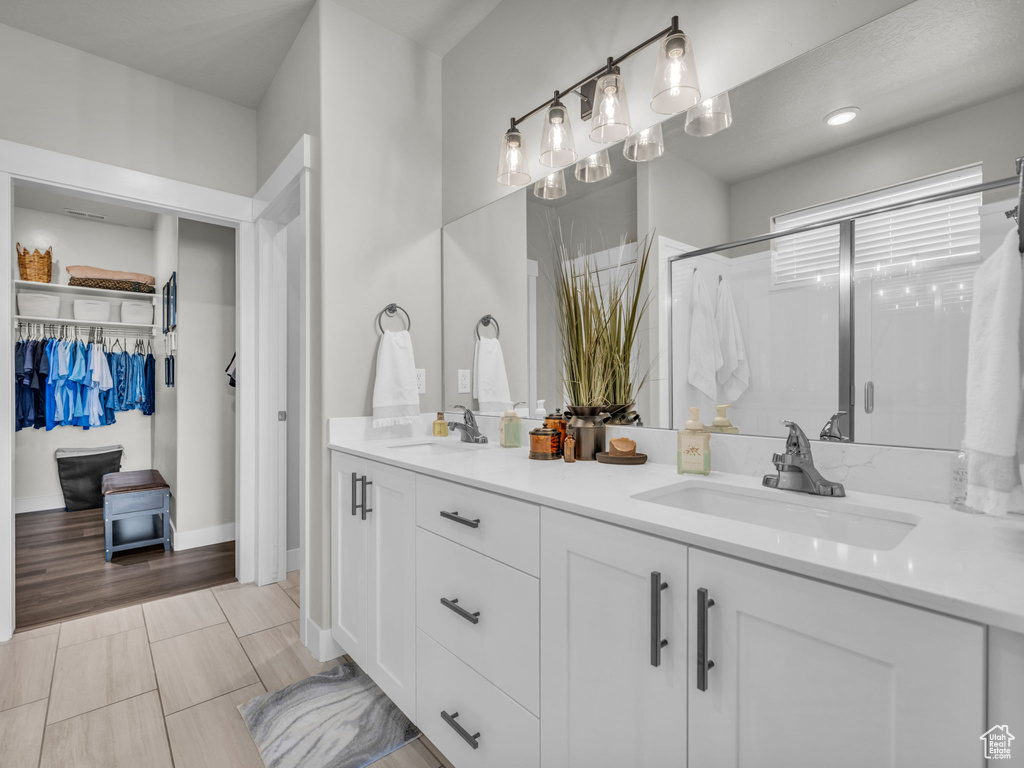 Full bathroom featuring double vanity, a stall shower, and a spacious closet