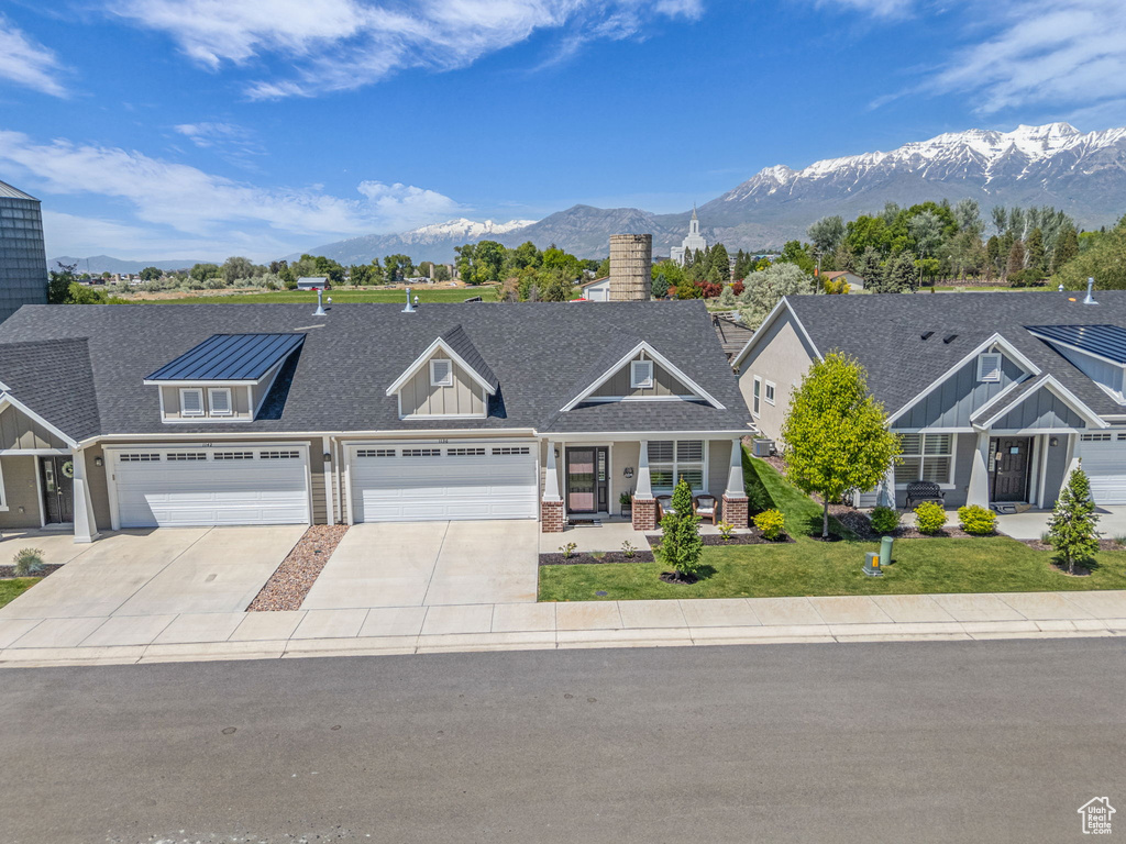 View of front of property featuring a mountain view, driveway, a chimney, and a front yard