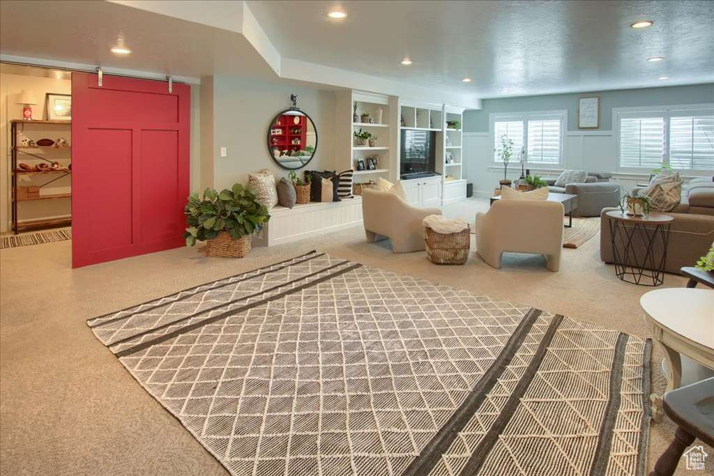 Carpeted living room featuring a barn door, recessed lighting, and built in shelves