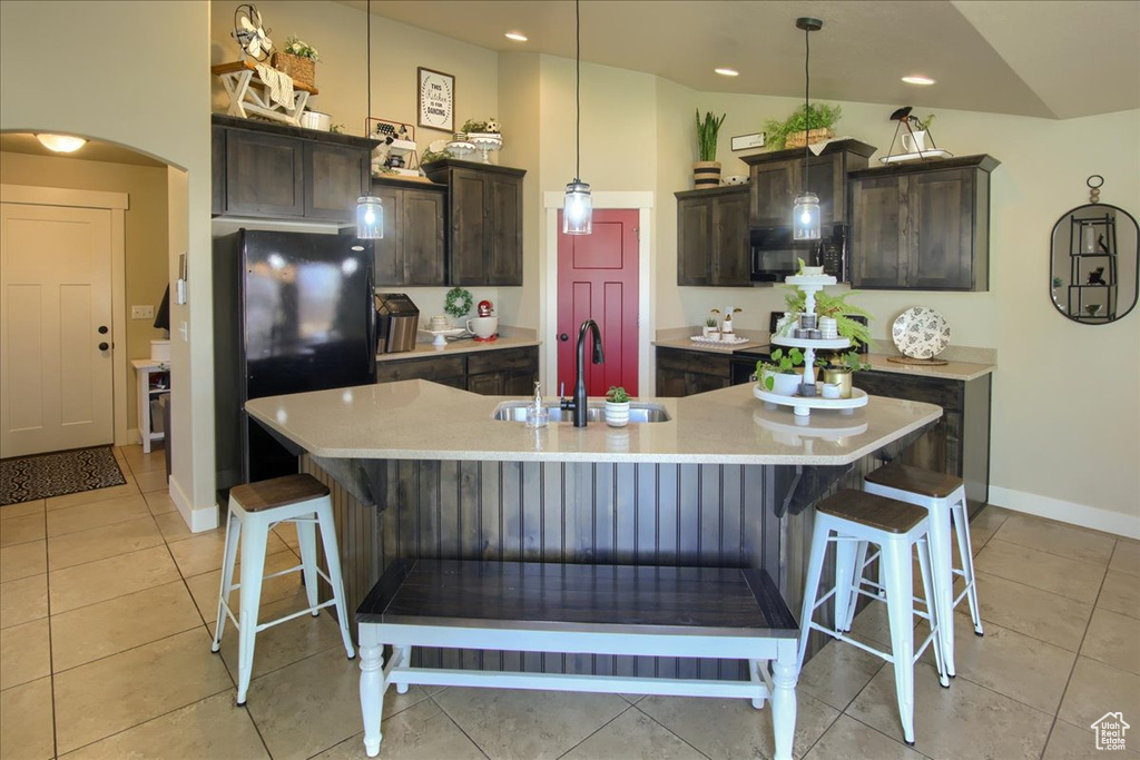 Kitchen with a sink, black appliances, a kitchen breakfast bar, light countertops, and lofted ceiling