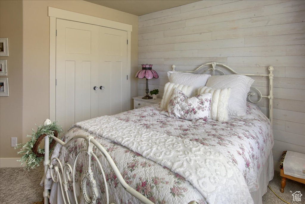 Bedroom with carpet floors, wooden walls, and a closet