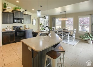Kitchen featuring black appliances, a sink, light countertops, a kitchen island with sink, and recessed lighting