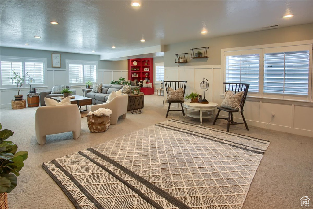 Living room featuring a decorative wall, carpet, recessed lighting, and a wainscoted wall