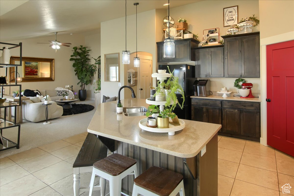Kitchen with a sink, freestanding refrigerator, light tile patterned floors, vaulted ceiling, and a ceiling fan