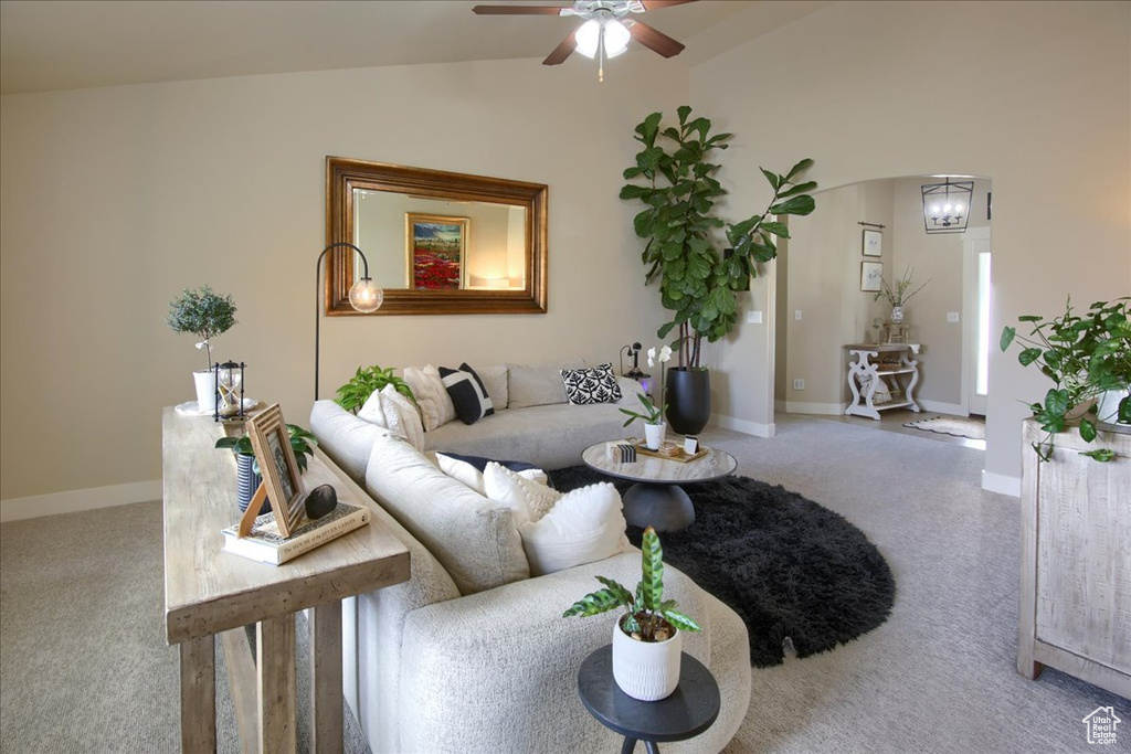 Living area featuring carpet flooring, lofted ceiling, ceiling fan, arched walkways, and baseboards