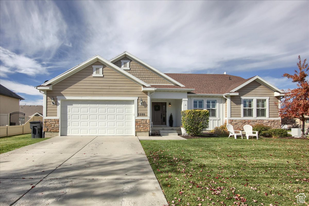 Craftsman inspired home with stone siding, a garage, and a front yard