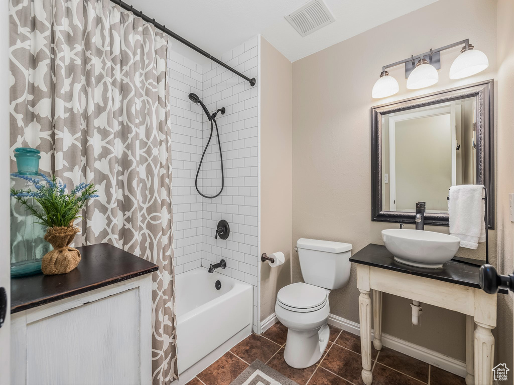 Full bathroom with shower / bath combo, toilet, vanity, tile patterned floors, and baseboards