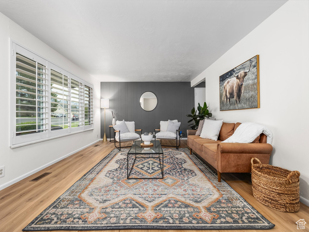 Living room with an accent wall, wood finished floors, and baseboards