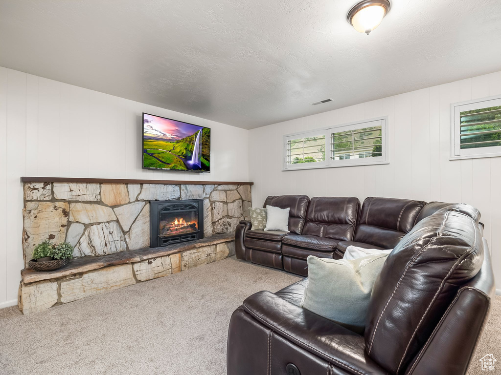 Carpeted living room with a stone fireplace