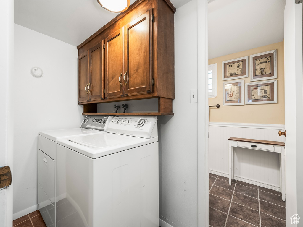 Laundry area with cabinet space, washer and clothes dryer, wainscoting, and dark tile patterned flooring