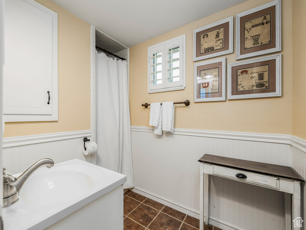 Bathroom with a wainscoted wall, vanity, tile patterned floors, and curtained shower