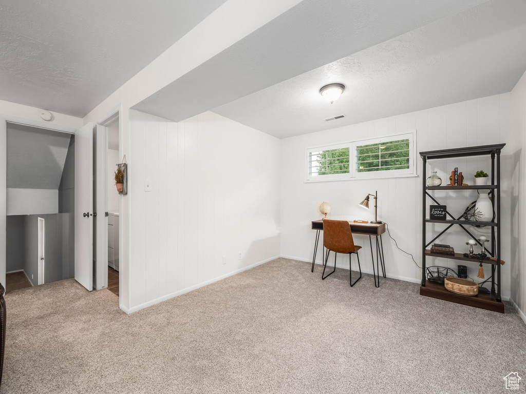 Basement with carpet floors, a textured ceiling, baseboards, and an office area