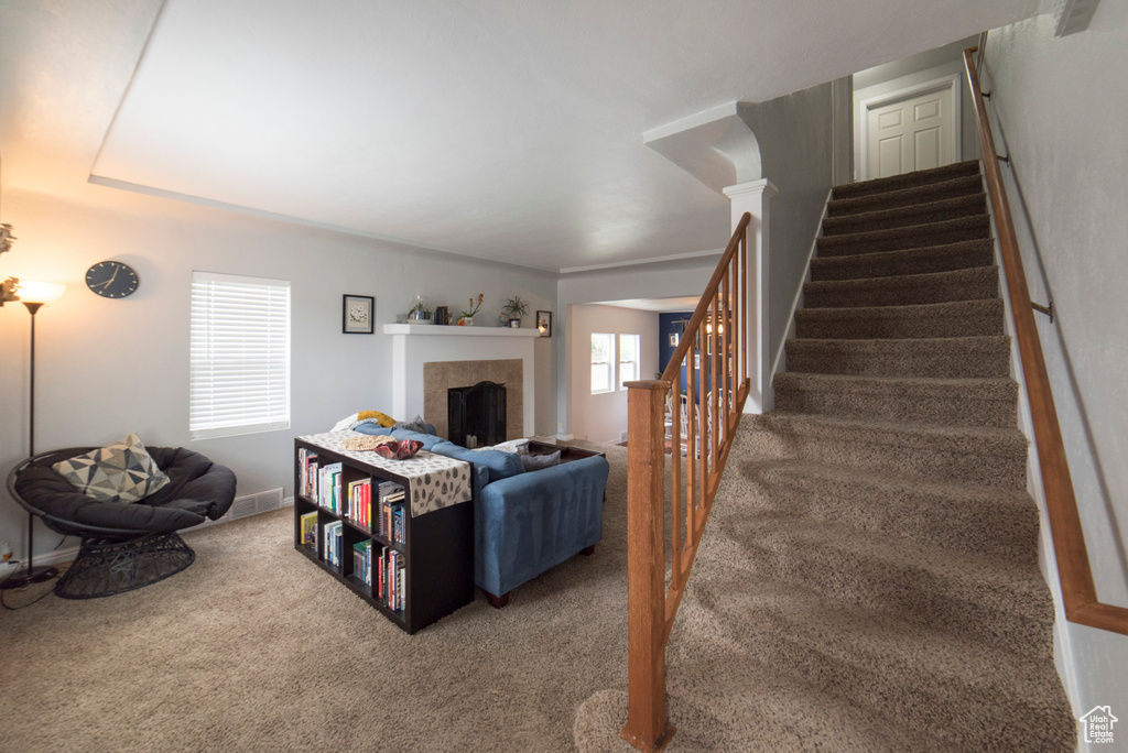 Carpeted living room with stairway, a tiled fireplace, and baseboards