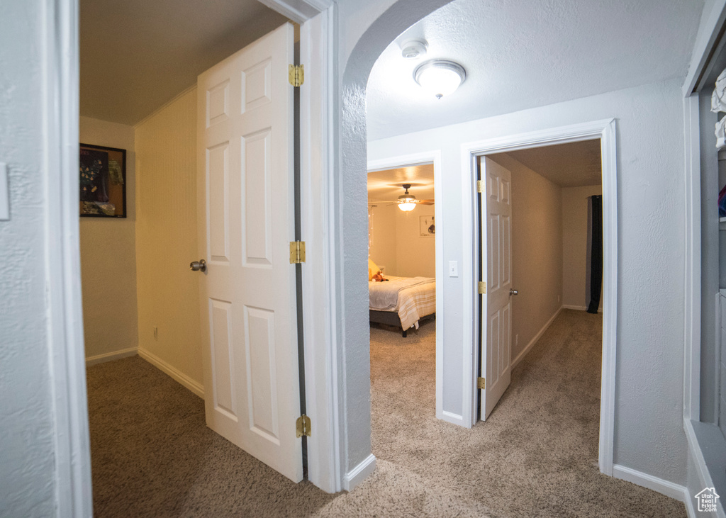 Hallway with carpet flooring, arched walkways, and baseboards