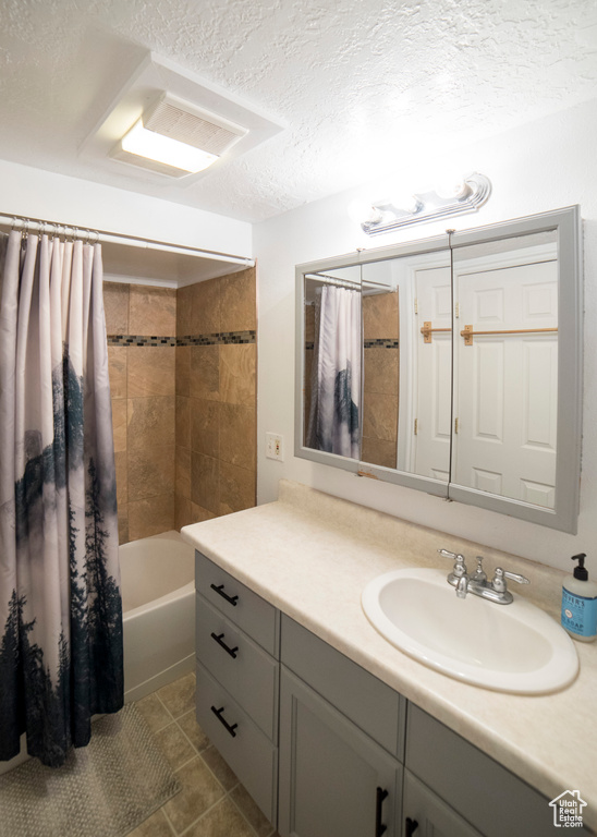 Bathroom with vanity, a textured ceiling, shower / bath combo with shower curtain, and tile patterned floors