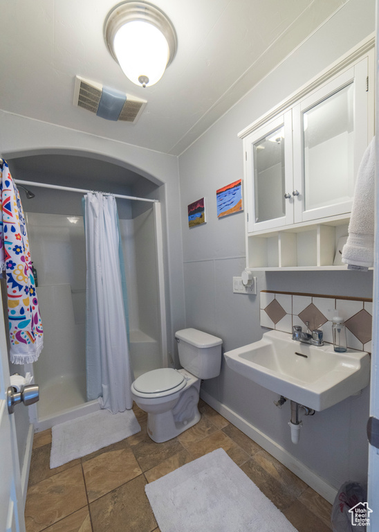 Full bath with a shower stall, toilet, decorative backsplash, and stone finish flooring