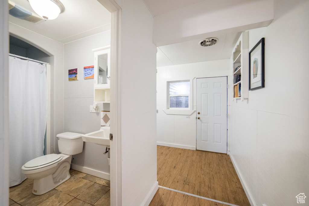 Full bath featuring toilet, baseboards, a shower with curtain, and wood finished floors