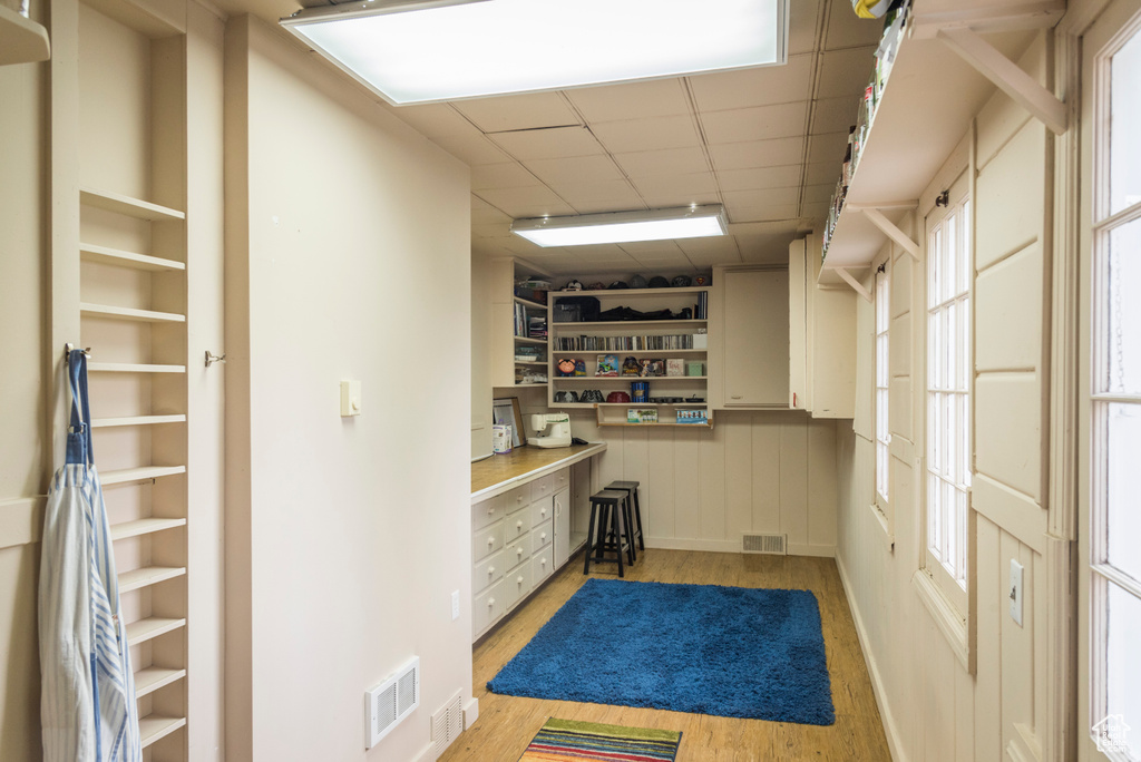 Interior space featuring built in study area, light wood-type flooring, and a drop ceiling