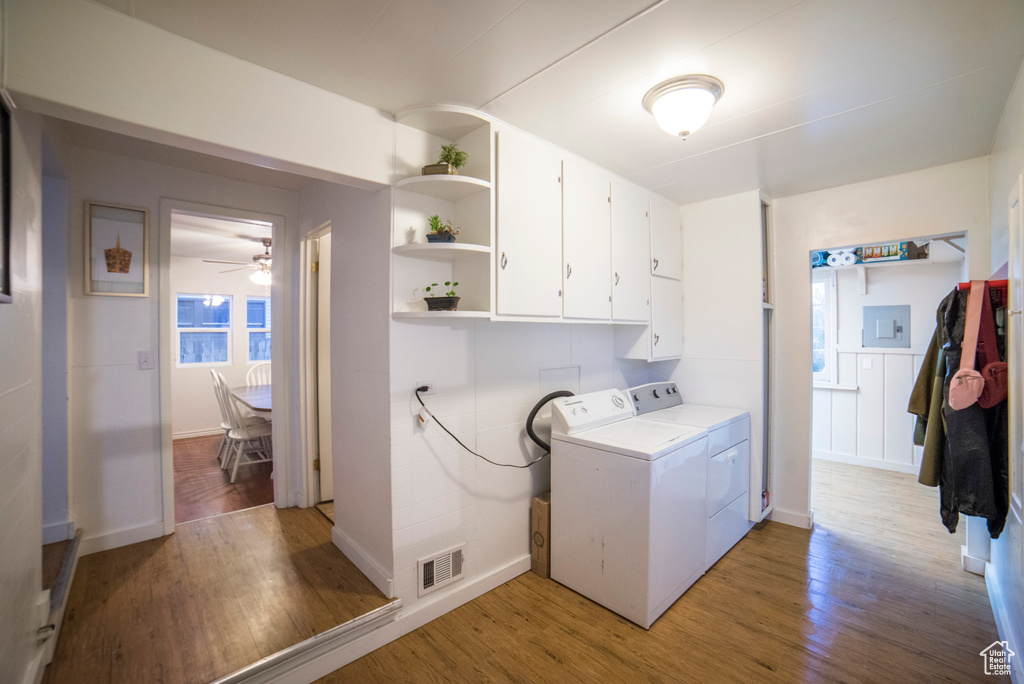 Laundry room featuring cabinet space, independent washer and dryer, light wood-style floors, electric panel, and baseboards