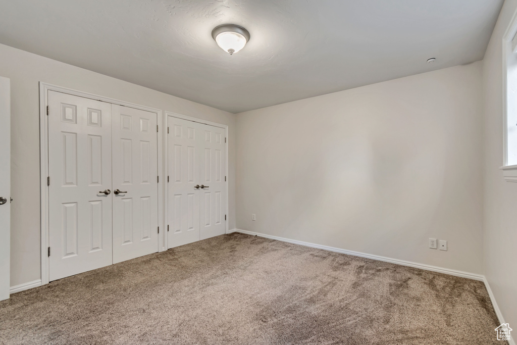 Unfurnished bedroom with multiple closets, carpet flooring, and baseboards