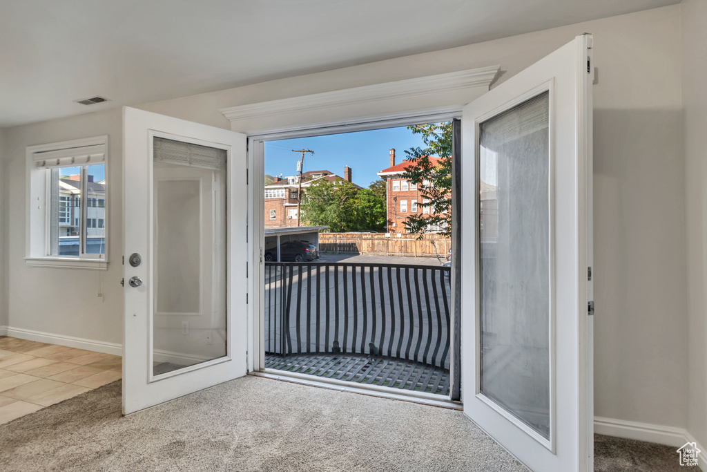 Doorway to outside with carpet flooring, baseboards, and tile patterned floors
