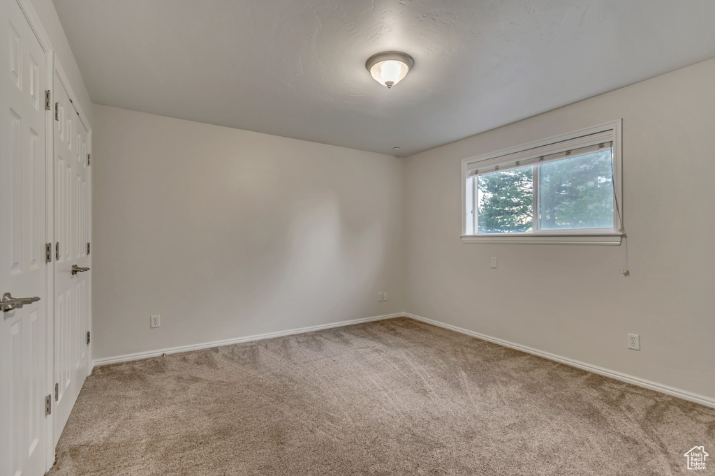 Carpeted spare room featuring baseboards