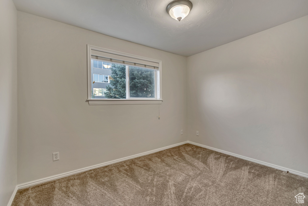 Spare room featuring carpet flooring and baseboards